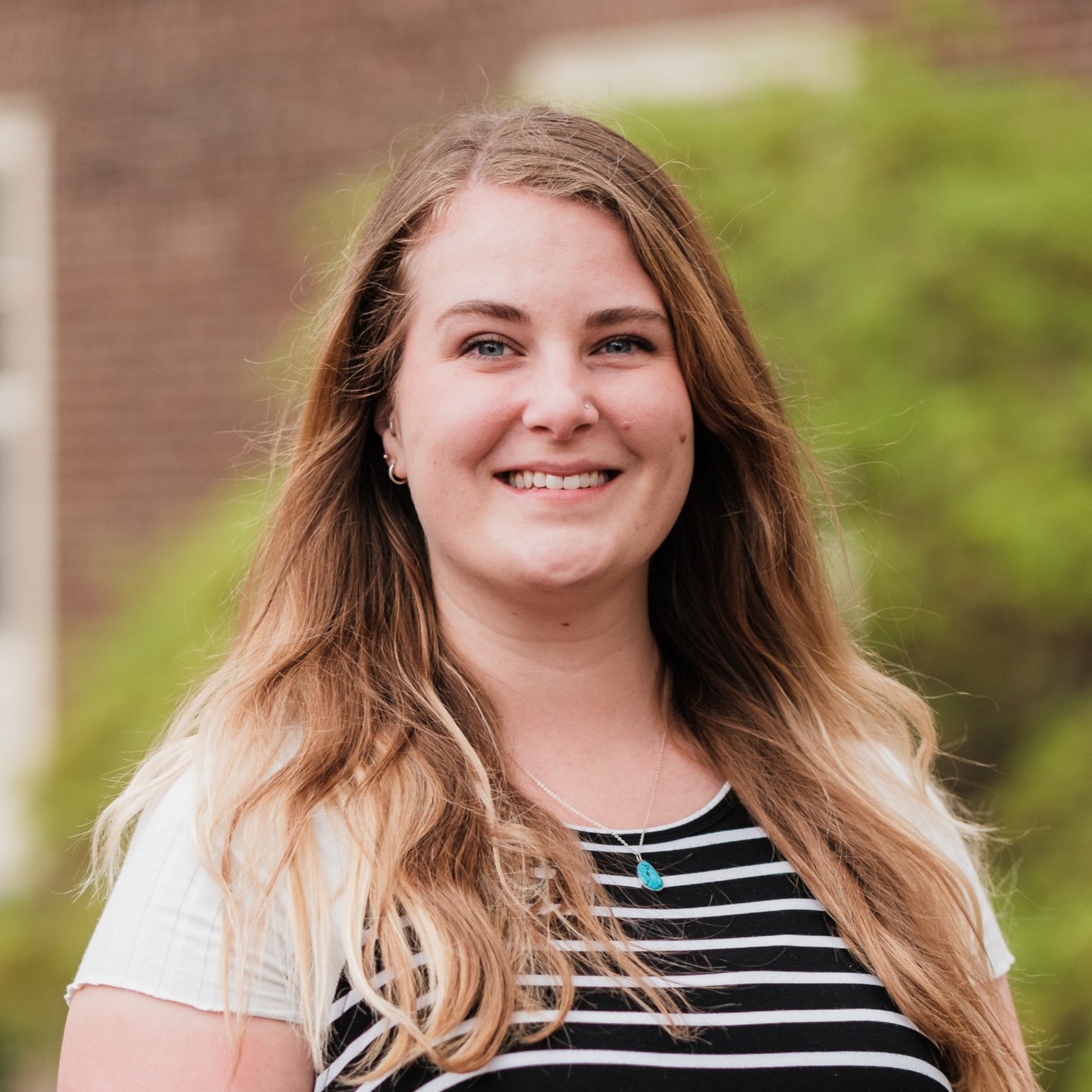 Ali Rill, a white woman with blonde hair, smiling and standing outside Grange building