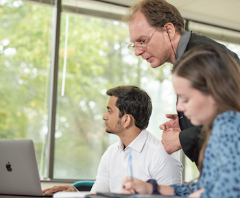 Professor and students working with a laptop.