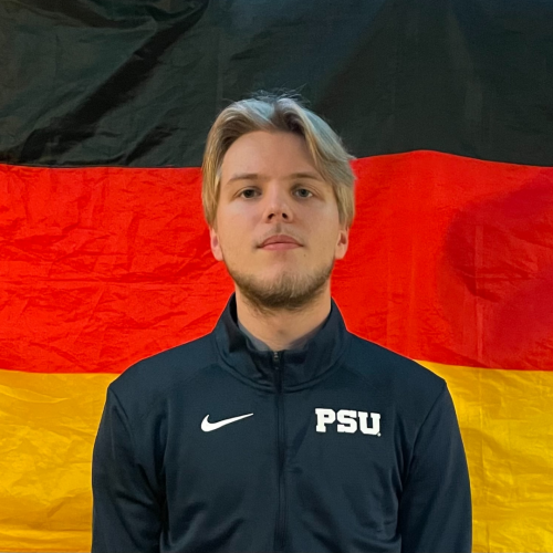 Caucasian male Penn State student standing in front of a German flag.