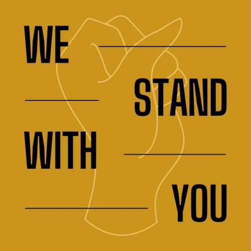 Black text reading We Stand With You with the outline of a closed fist in the background.