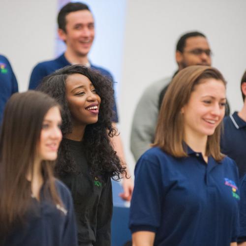 Students in the Essence of Joy choir smile broadly as they sing during a rehearsal.