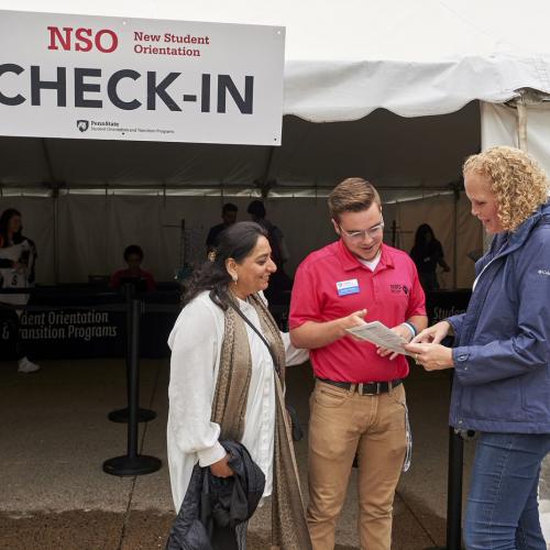 Orientation Leader Jordan talks to two parents outside of the NSO check-in tent. 
