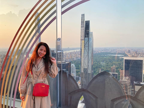 Asian female standing atop a skyscraper in New York City with Central Park in the background.